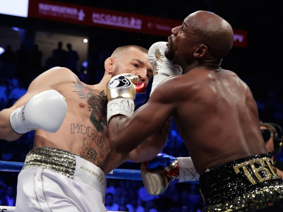 Conor McGregor hits Floyd Mayweather Jr. in a super welterweight boxing match Saturday, Aug. 26, 2017, in Las Vegas. (AP Photo/Isaac Brekken)