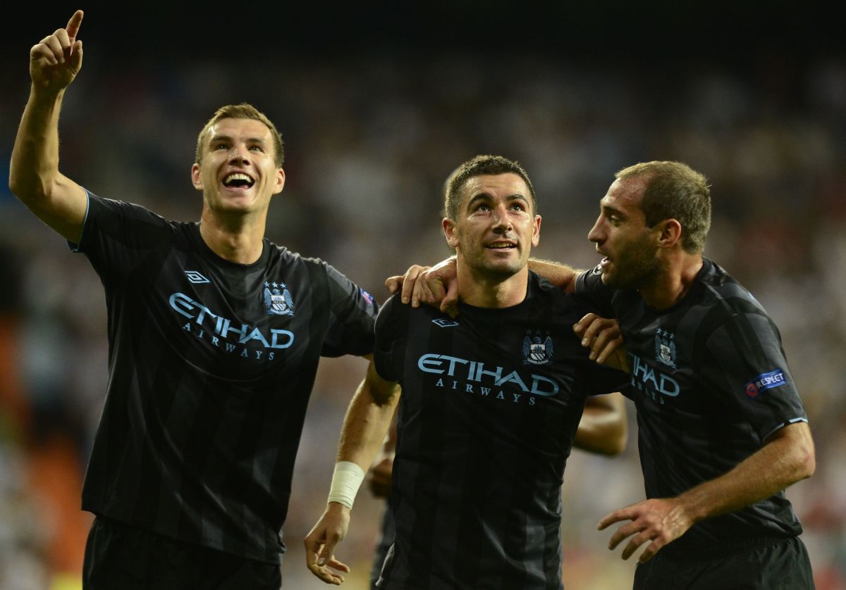 Manchester City's Serbian defender Aleksandar Kolarov (C), Manchester City's Bosnian forward Edin Dzeko (L) and Manchester City's  Argentinian player Pablo Zabaleta (R) celebrate after scoring their second goal during the Champions League Group D football match Real Madrid vs Mancherter City at Santiago Bernabeu stadium in Madrid on September 18, 2012.  AFP PHOTO / JAVIER SORIANO        (Photo credit should read JAVIER SORIANO/AFP/GettyImages)