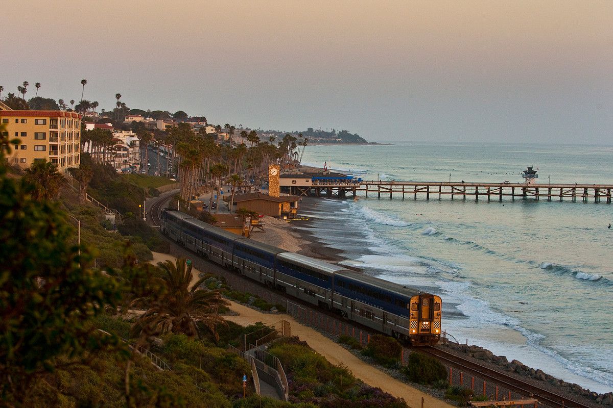 The Amtrak Pacific Surfliner train travels past the the San Clemente pier at sunset.