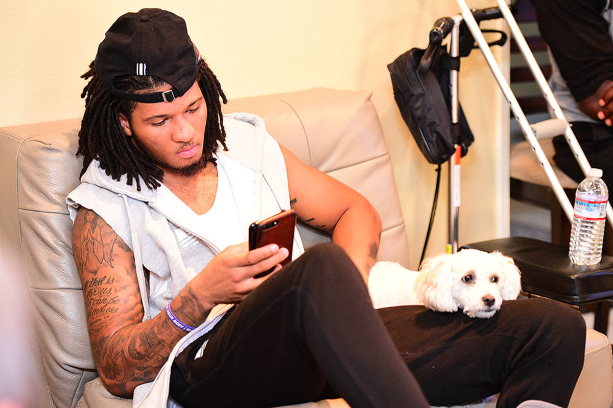 Sidney Jones checks out his two phones with his dog, Zyha.