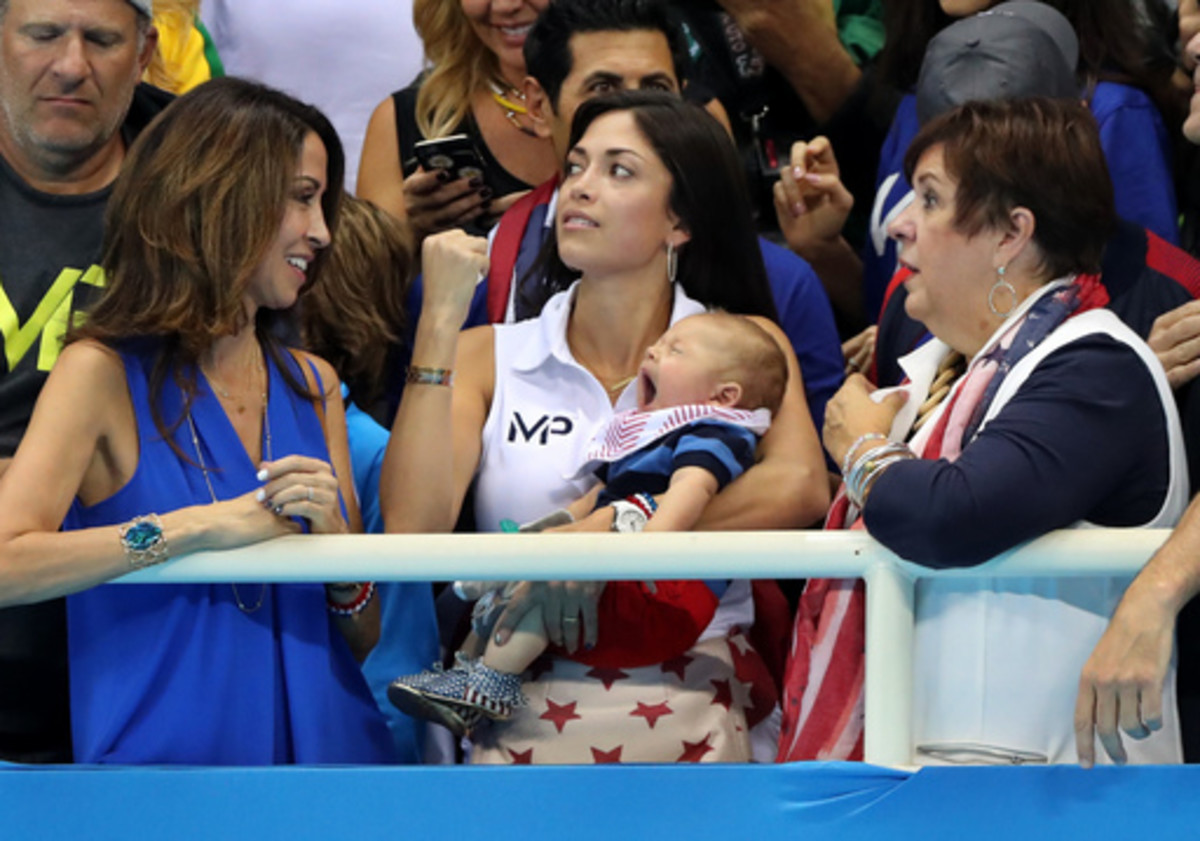 Nicole Johnson, fiance of United States' Michael Phelps, holds their baby Boomer, as she stands along with Phelps' mother Debbie and sister during the men's 4 x 100-meter medley relay final during the swimming competitions at the 2016 Summer Olympics, Sat