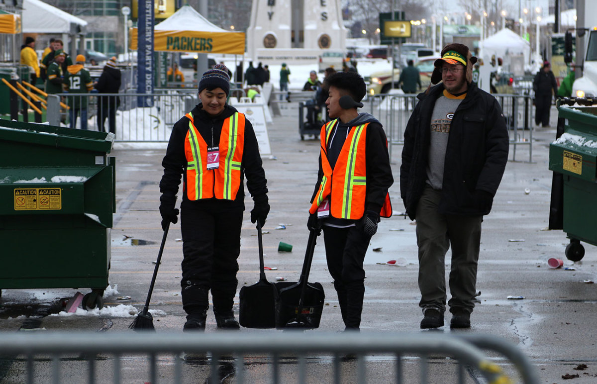 Adam Vang, center, and friends help clean up the grounds outside Lambeau. 