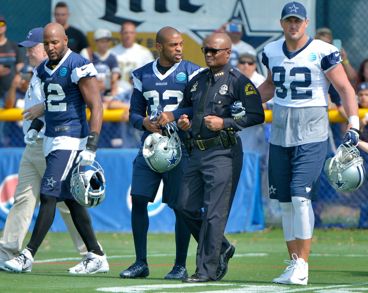 Dallas Police chief David Brown is escorted onto the field by Orlando Scandrick (32) and Jason Witten before Saturday’s practice in Oxnard, Calif.