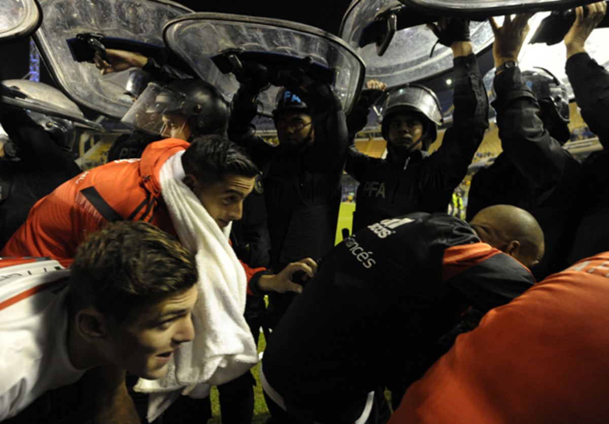 River Plate players shield themselves with police while under assault from Boca Juniors fans.