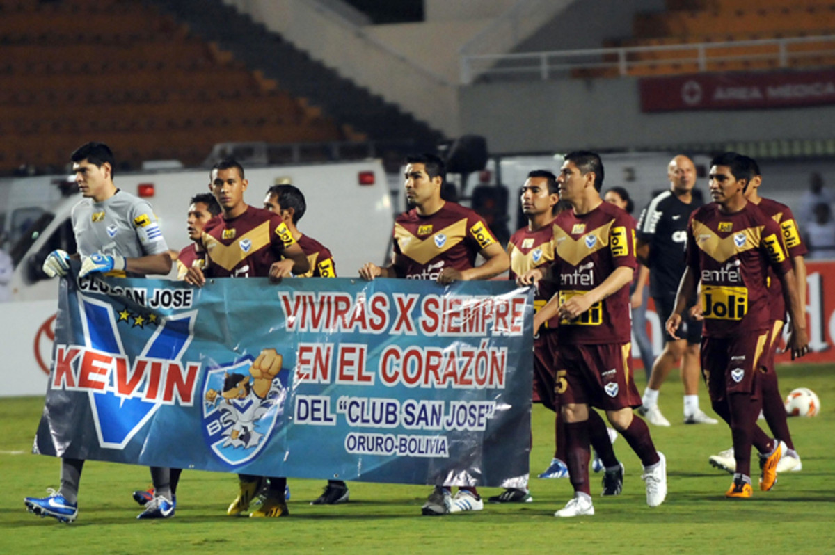 Players from Bolivian club San Jose carry a banner in remembrance of Kevin Espada, a fan who was killed by a thrown flare in a match against Brazil's Corinthians.