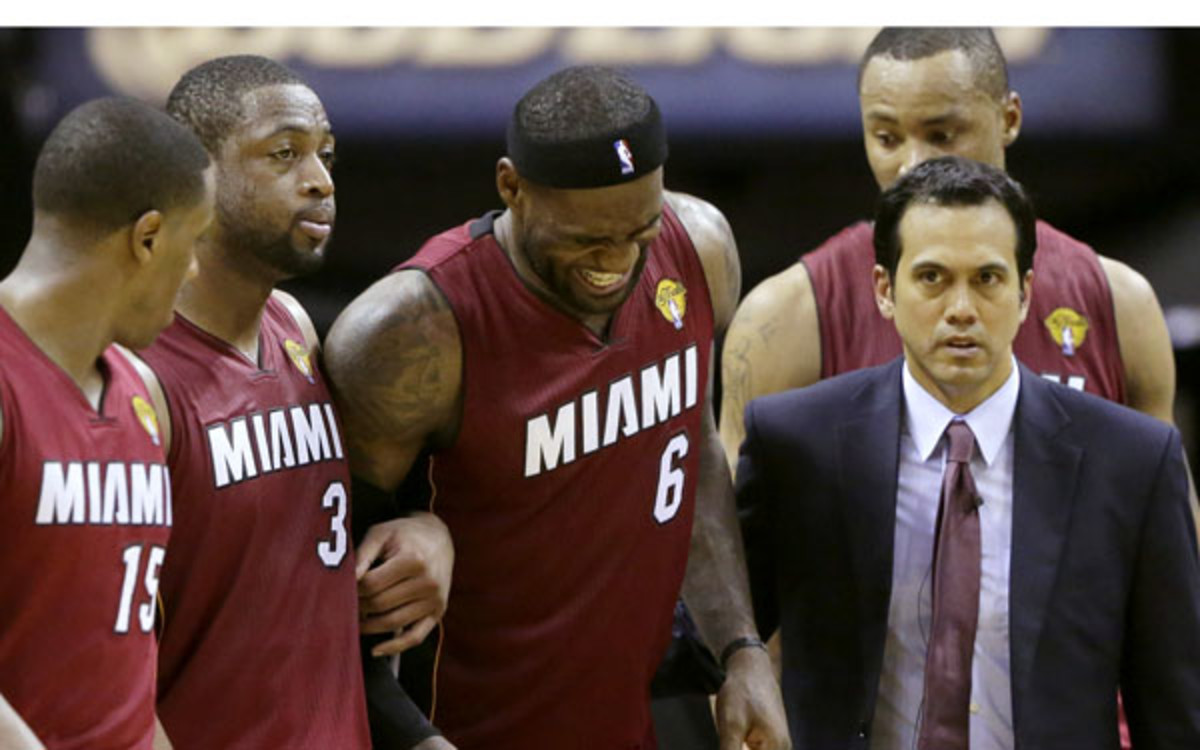 LeBron James is helped by teammates and coach Erik Spoelstra after experiencing cramps. (AP Photo/Eric Gay)