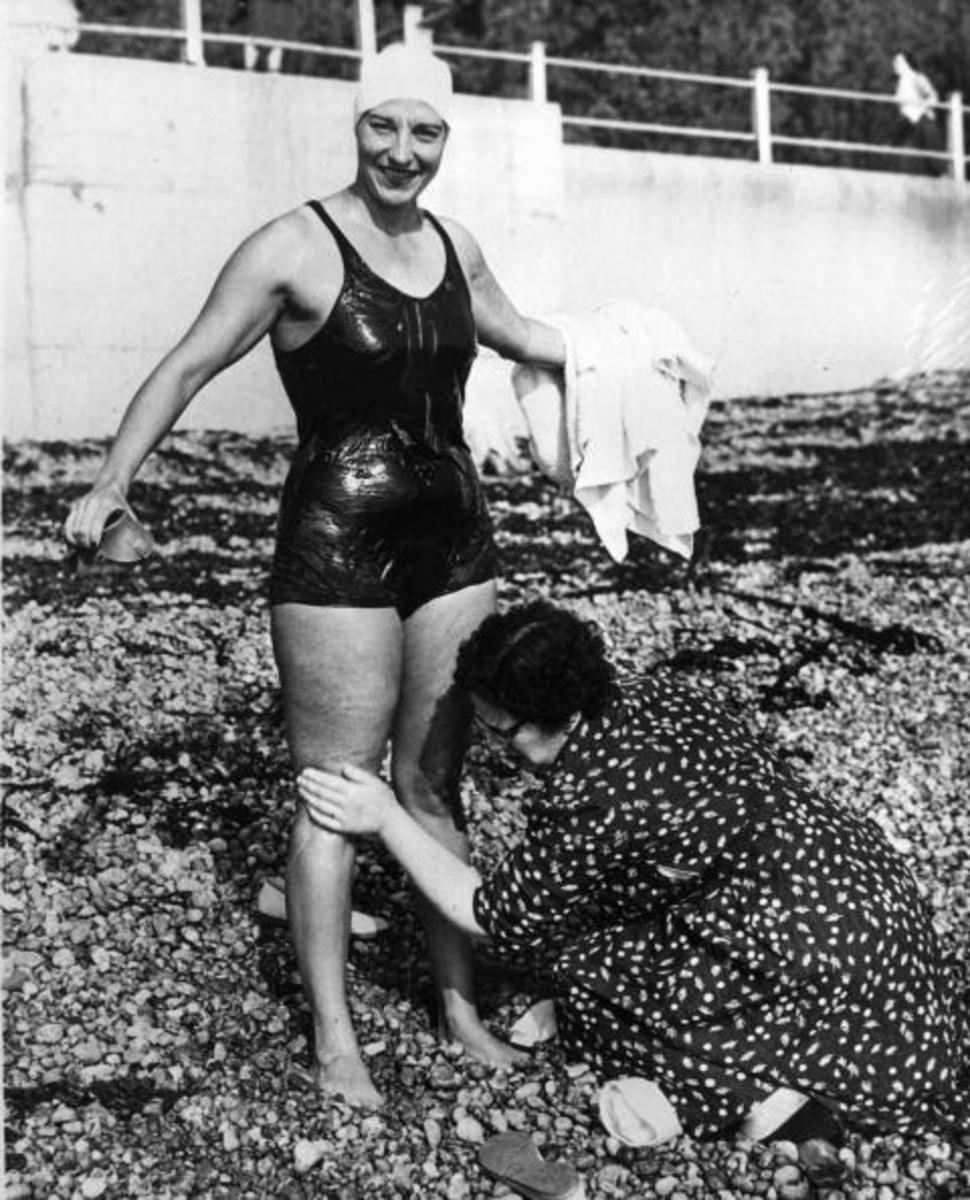 11th October 1955: Miss Florence Chadwick (1917 - 1995), a swimmer from San Diego in California, is being given a rub-down before entering the water at St Margaret's Bay near Dover, Kent for her attempt at a non-stop double crossing of the English channel. She first swam both ways from France to England in 1950 and from England to France in 1951 and 1955.