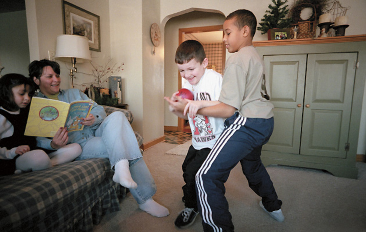 Jordan (right), adopted by the Millers, plays with his brother Cameron as sister McKenzie and mother Shelly look on.