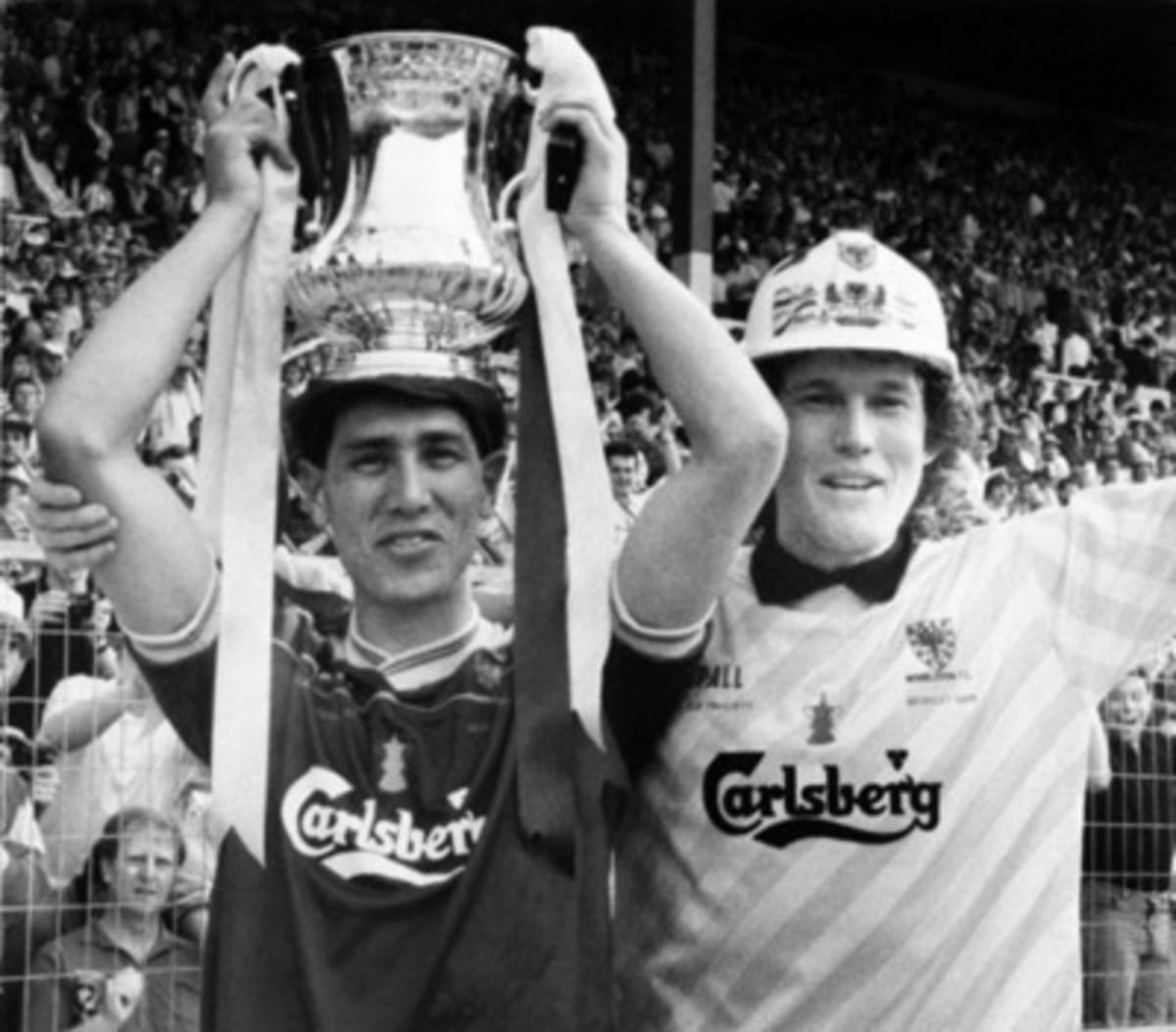 Wimbledon's Lawrie Sanchez holds the FA Cup as captain and goalkeeper David Beasant acknowledges the fans after defeating Liverpool 1-0 in the 1988 FA Cup final.