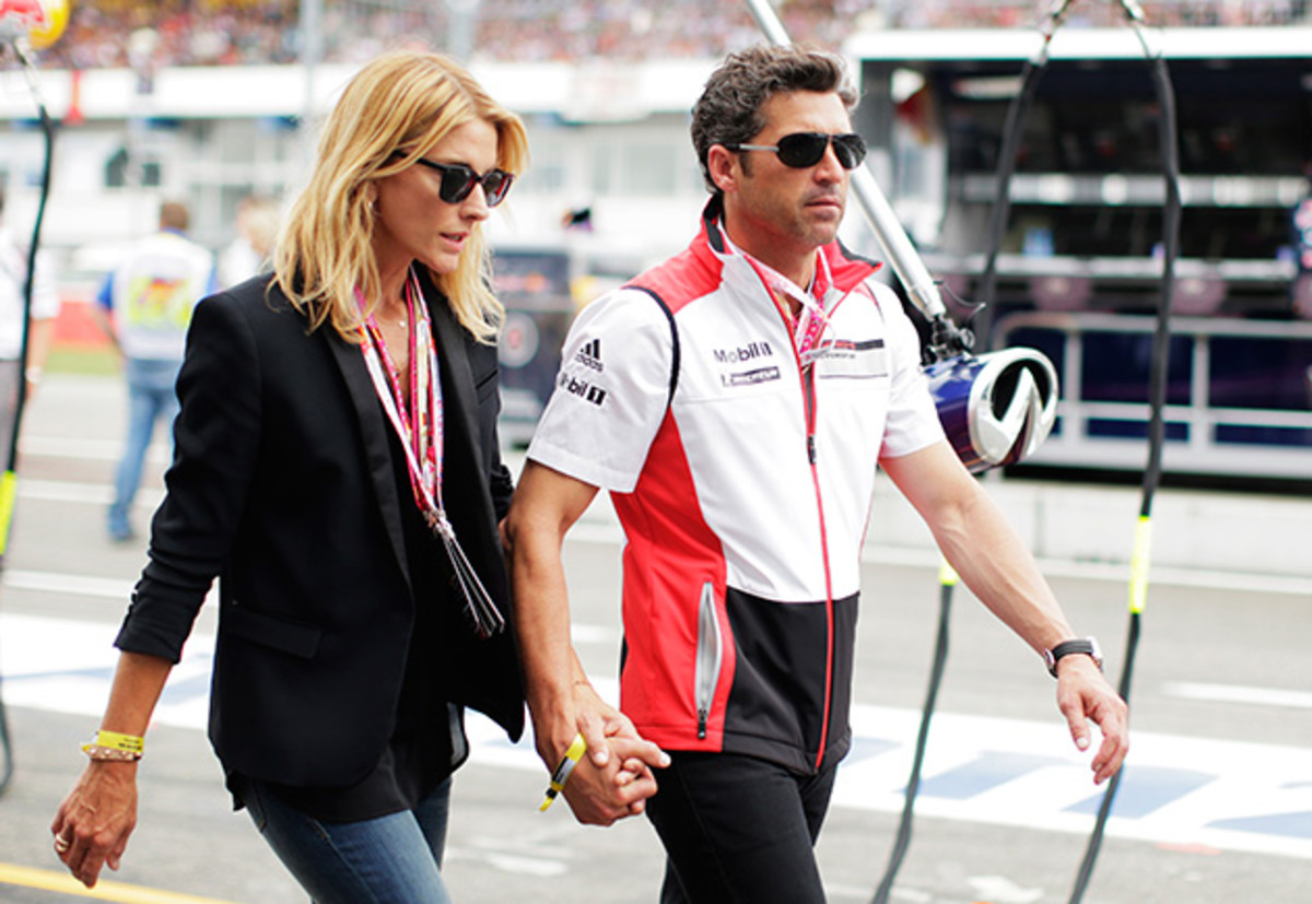 Driver and actor Patrick Dempsey walks past the Infiniti Red Bull Racing garage with his wife Jill Fink before the German Grand Prix at Hockenheimring on July 20, 2014 in Hockenheim, Germany.