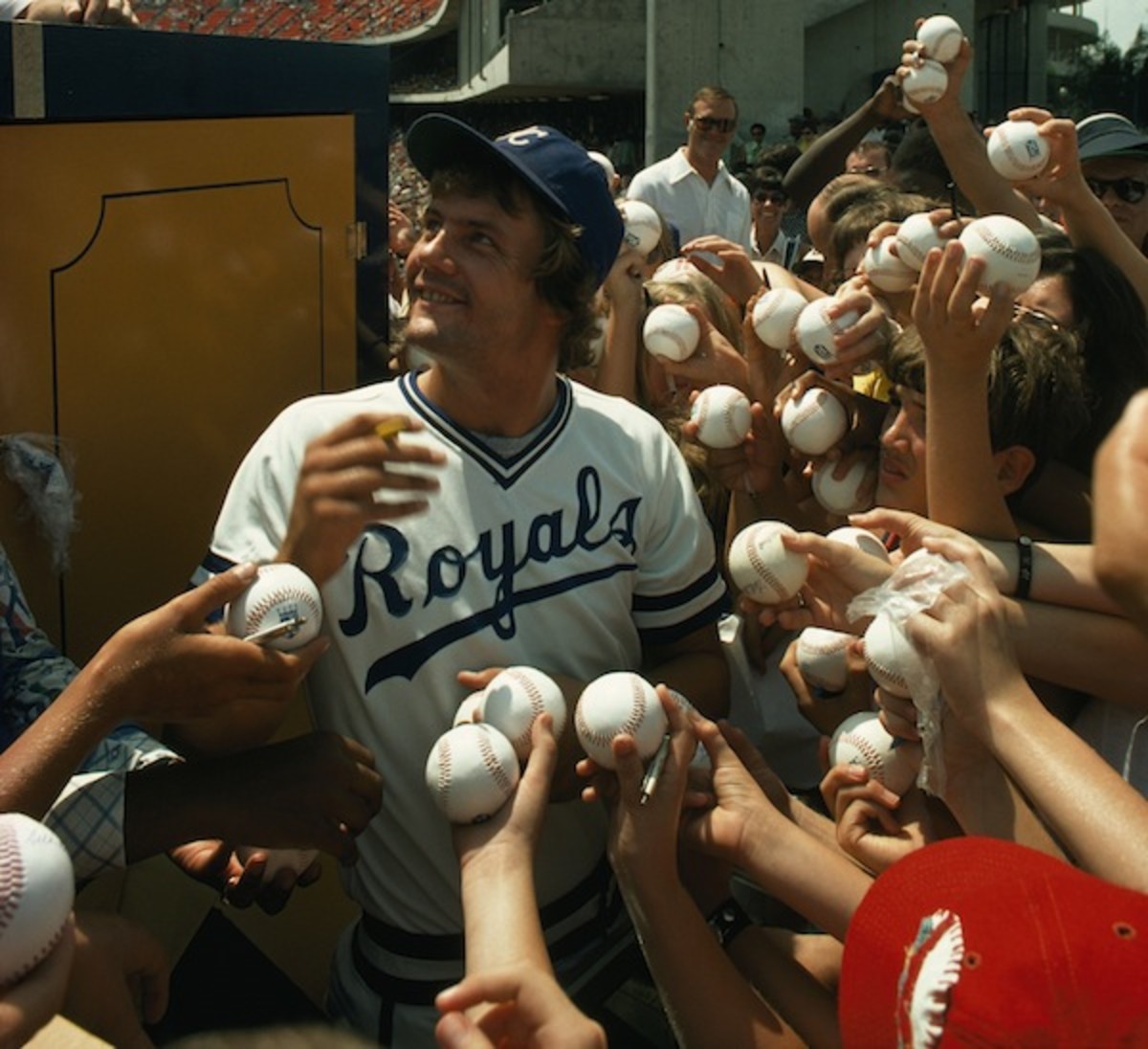 Young fans hold up baseballs for Royals star George Brett to sign