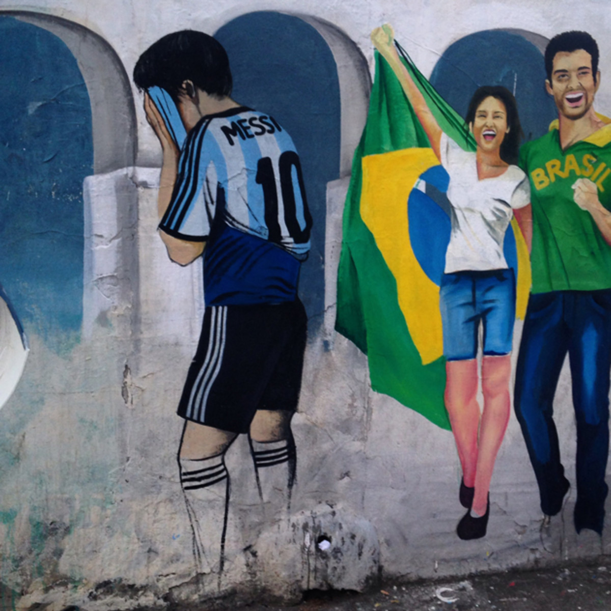 Roadside graffiti in Rio de Janeiro depicts a disappointed Lionel Messi, one with his head in his hands.