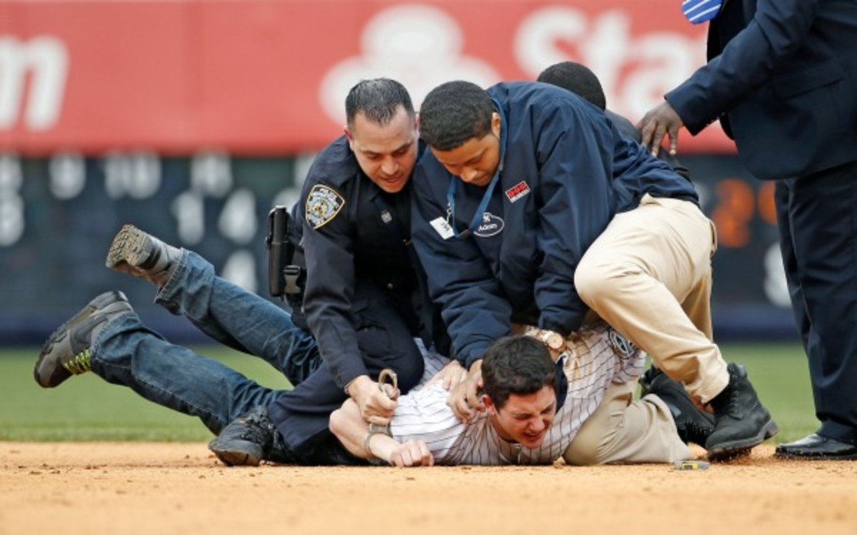 This fan is wrestled down by security personnel after coming on the field at Yankee Stadium. (AP Photo/Kathy Willens)