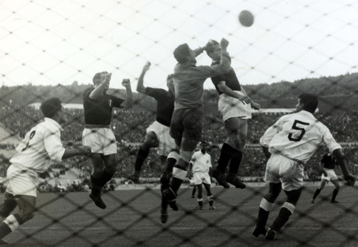 Benfica goalkeeper Pinto Machado punches the ball away under pressure from Torino's Romeo Menti, Émile Bongiorni and Valentino Mazzola a day before a tragic plane crash killed the Italian team.