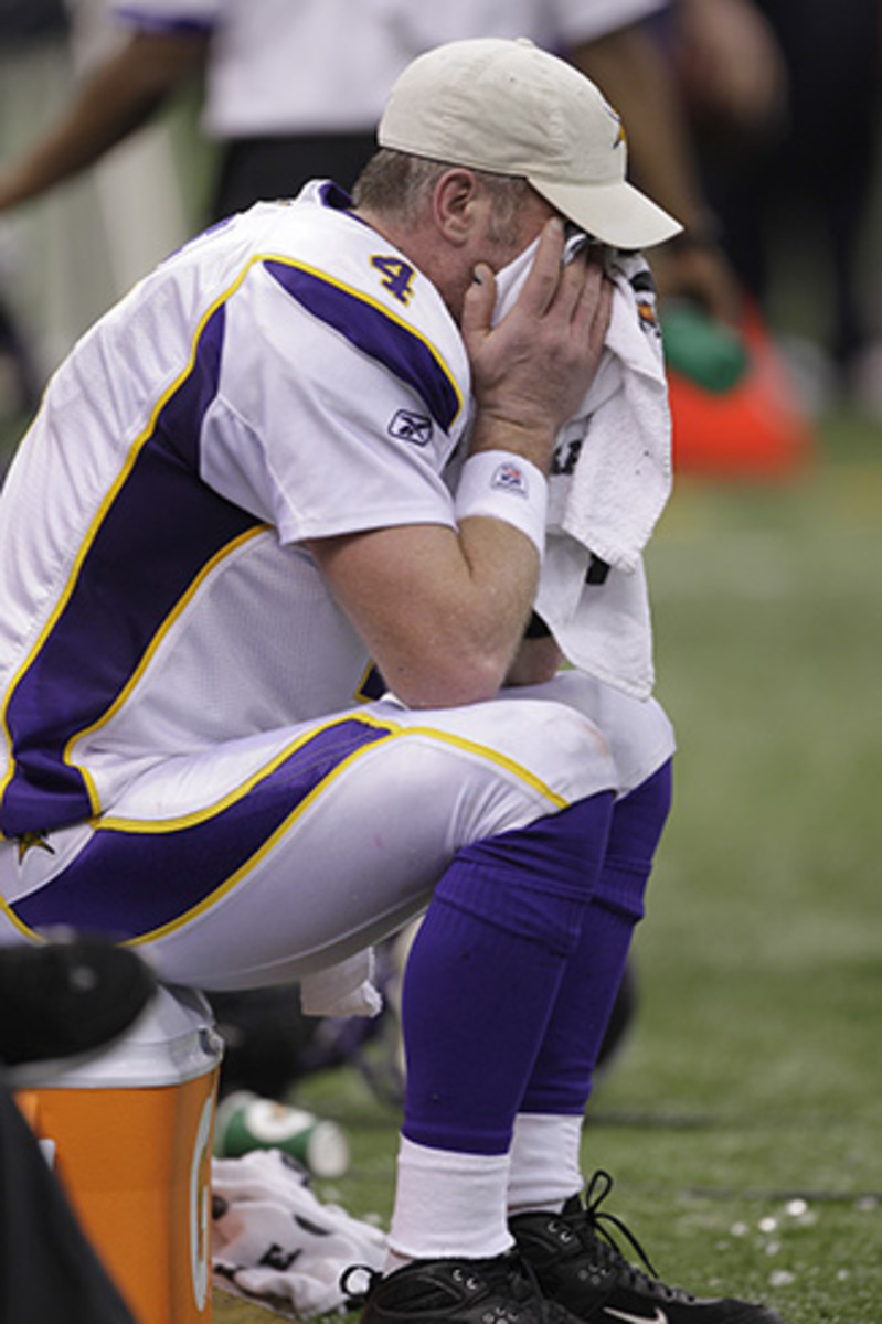 Favre covers his face on the sideline during the NFC championship. 