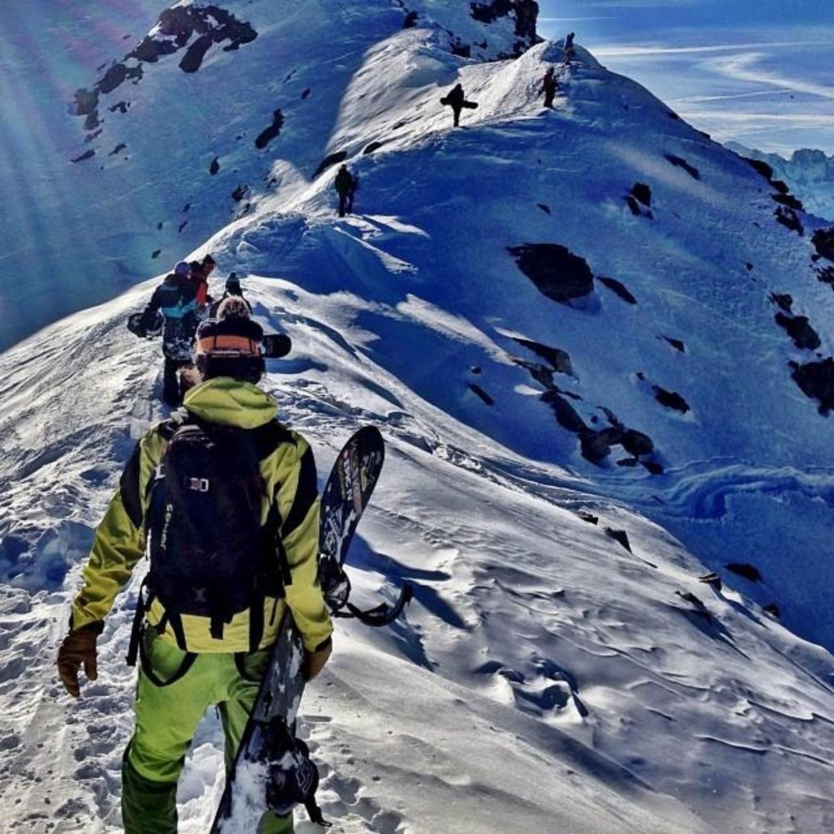 Snowboarder Jeremy Jones treks along the ridge of a mountain with his crew.