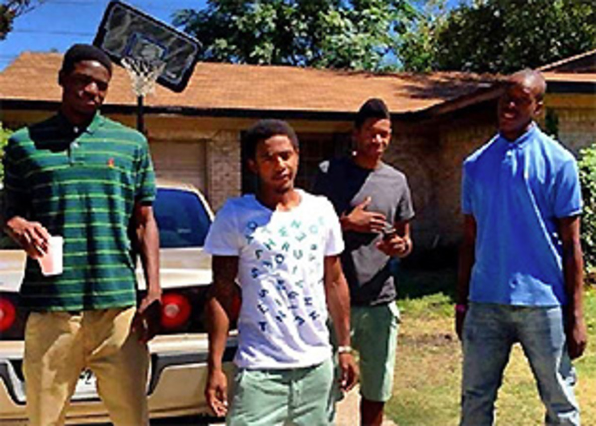 Johnathan Turner (left), Willie Hollins (second from left) and Troy Causey (right) stand in front of Willie's house with another young man.