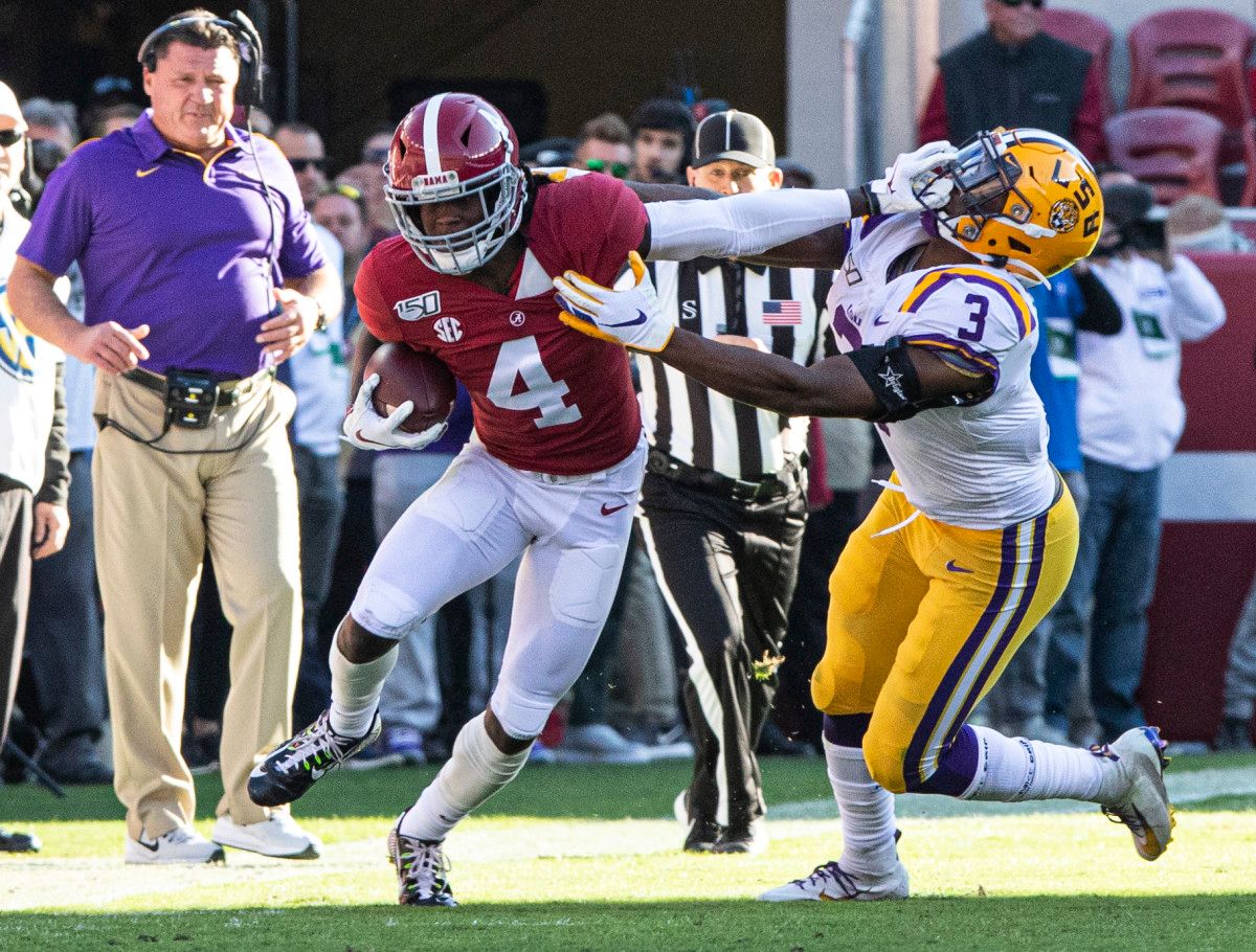 Jerry Jeudy tries to break a tackle in front of Ed Oregeron