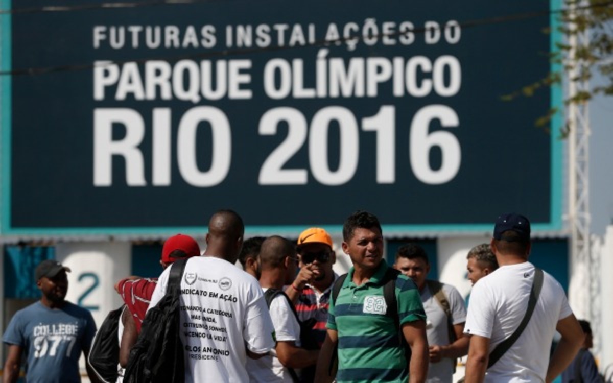 Striking workers stand in front the entrance of the Olympic Park, the main cluster of venues under construction for the 2016 Summer Olympic Games, in Rio de Janeiro, Brazil, Tuesday, April 8, 2014. The labor dispute centers around which union represents the construction workers, and also involves benefits and working conditions. (AP Photo/Silvia Izquierdo)