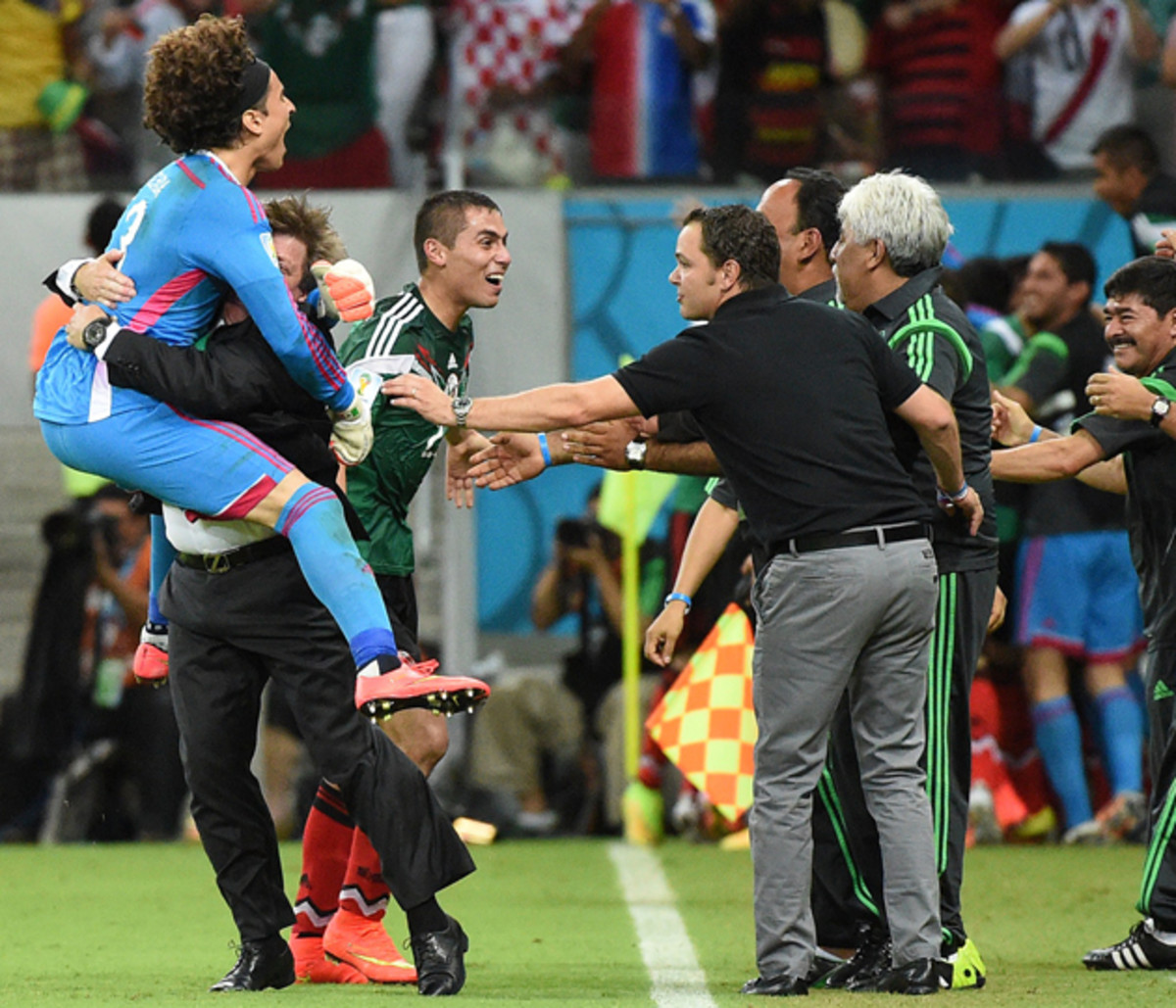 Miguel Herrera, second left, hoists goalkeeper Guillermo Ochoa in celebrating Mexico's 3-1 win over Croatia to seal El Tri's place in the round of 16.