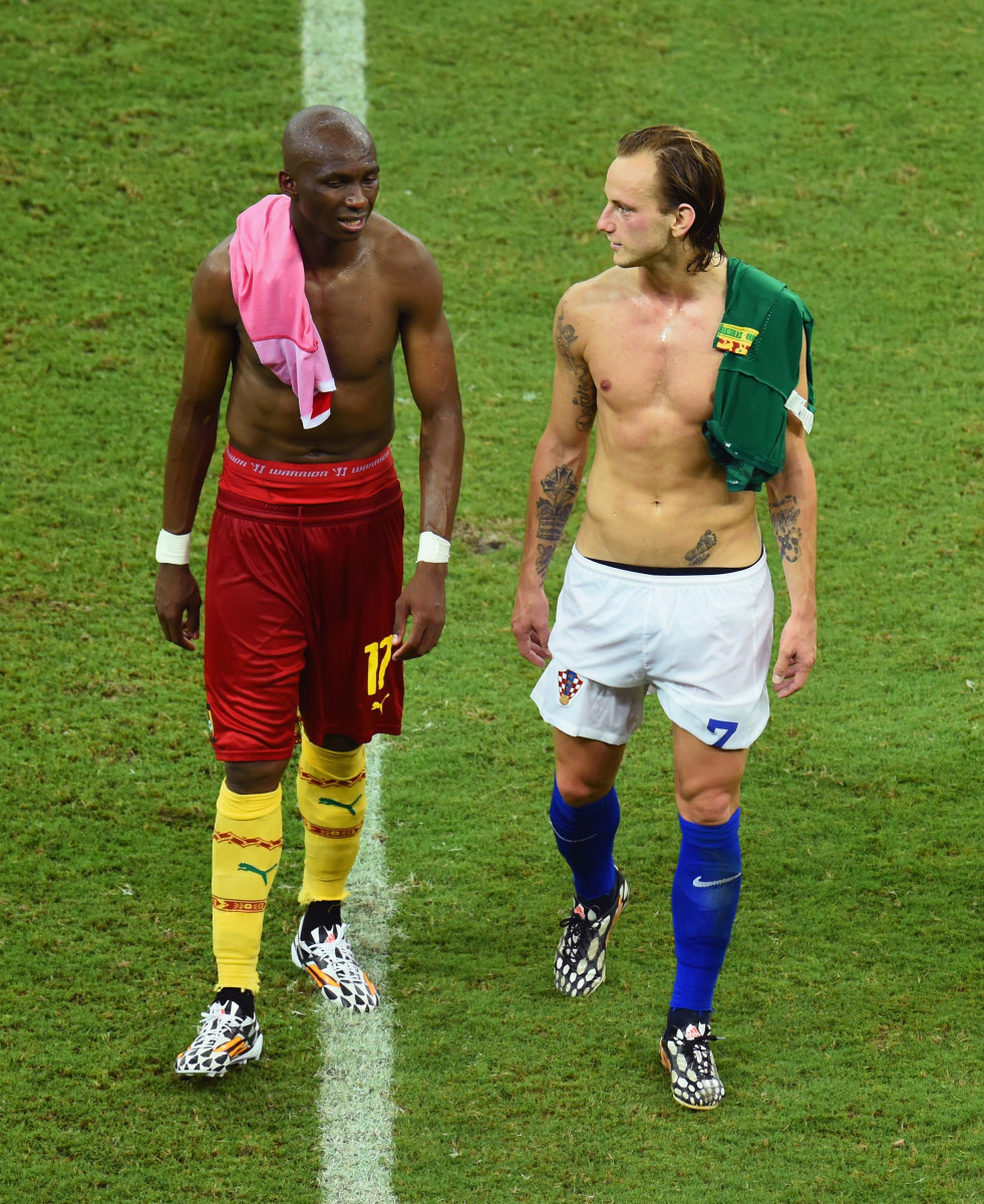 Stephane Mbia of Cameroon and Ivan Rakitic of Croatia walk off the field after Croatia's 4-0 win during the 2014 FIFA World Cup Brazil Group A match between Cameroon and Croatia