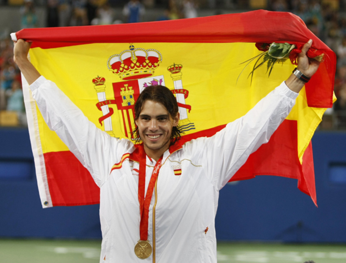 Nadal holds up the Spanish flag on the podium after receiving the gold medal.