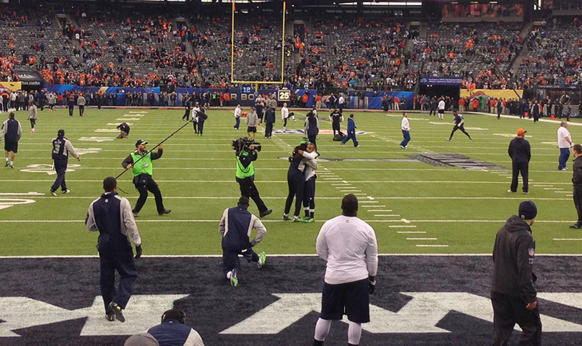 At center of frame, Baldwin and Sherman embrace during pre-game warmups, something the teammates do before every game. (The MMQB)