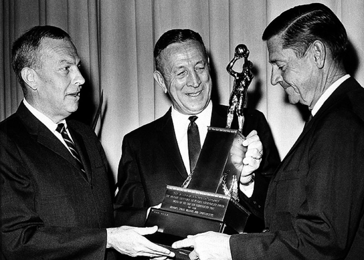 John Wooden (center) receives the AP championship trophy for his 1964 national championship season, in which his Bruins won 30 straight games.
