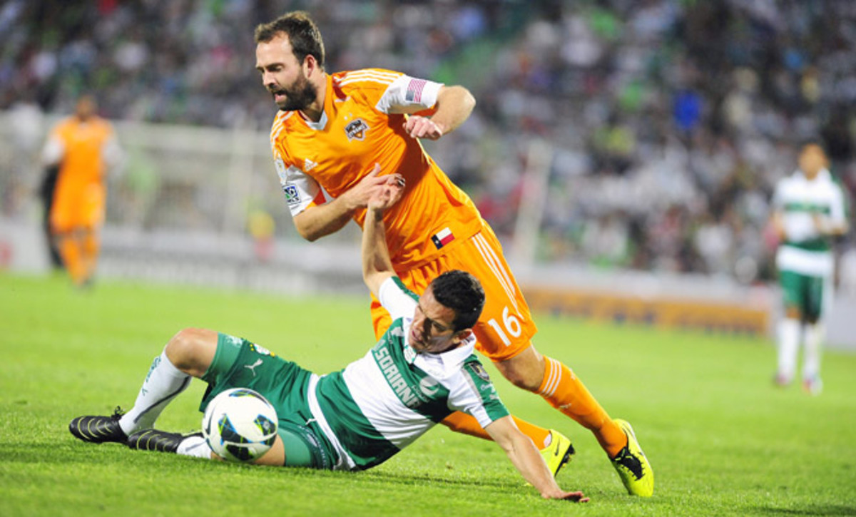 Dynamo midfielder Adam Moffat has the ball taken away with a tackle from Santos Laguna's Juan Pablo Rodriguez Wednesday night.