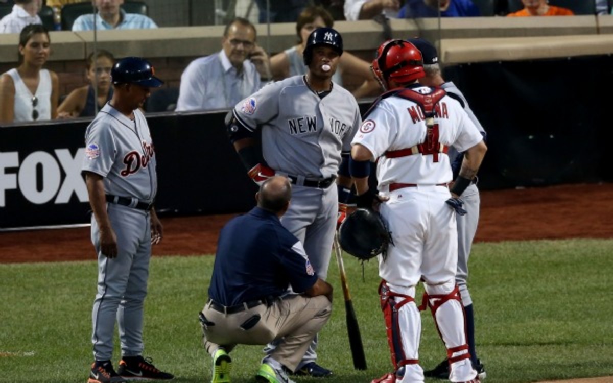 Yankees 2B Robinson Cano is examined after being hit by a pitch in the knee. (Bruce Bennett/Getty Images)