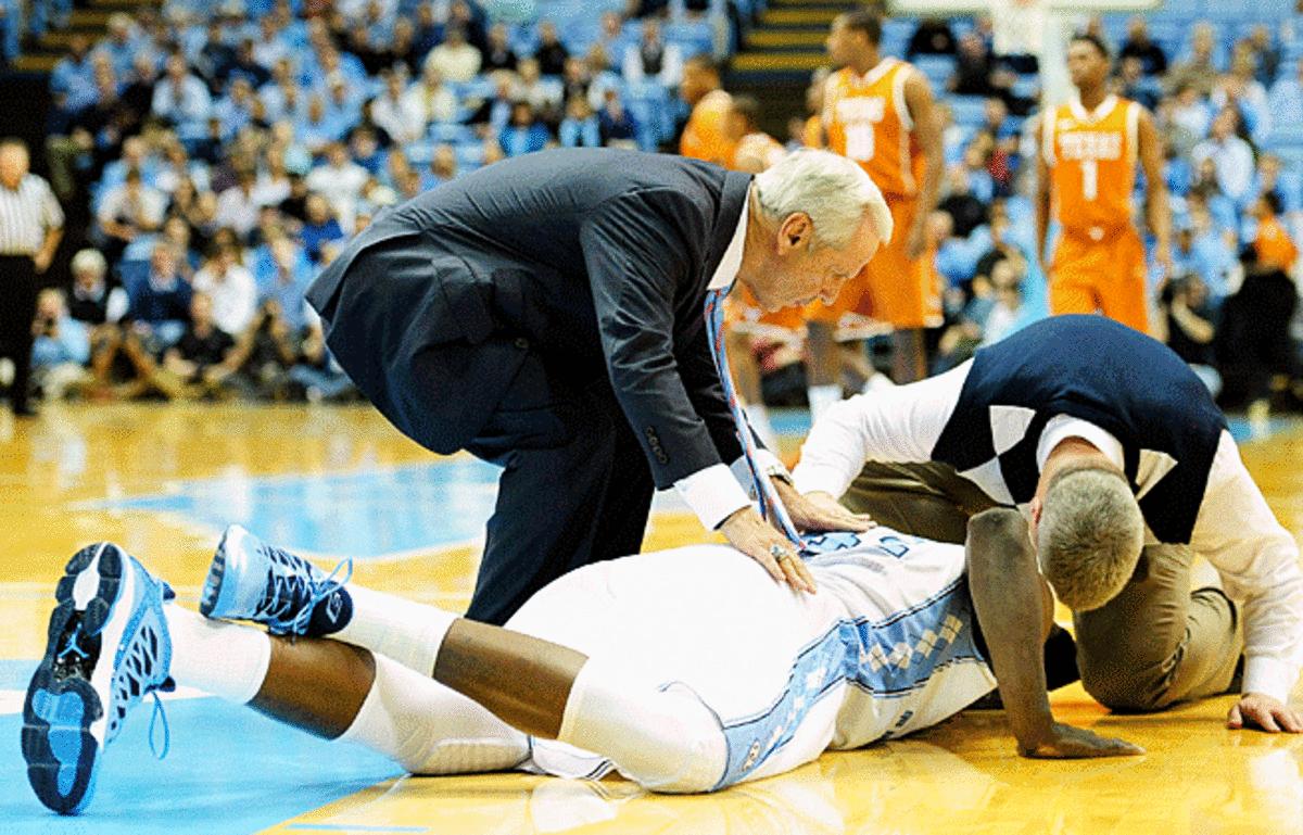 Head coach Roy Williams attends to Joel James after the UNC center hurt himself vs. Texas.