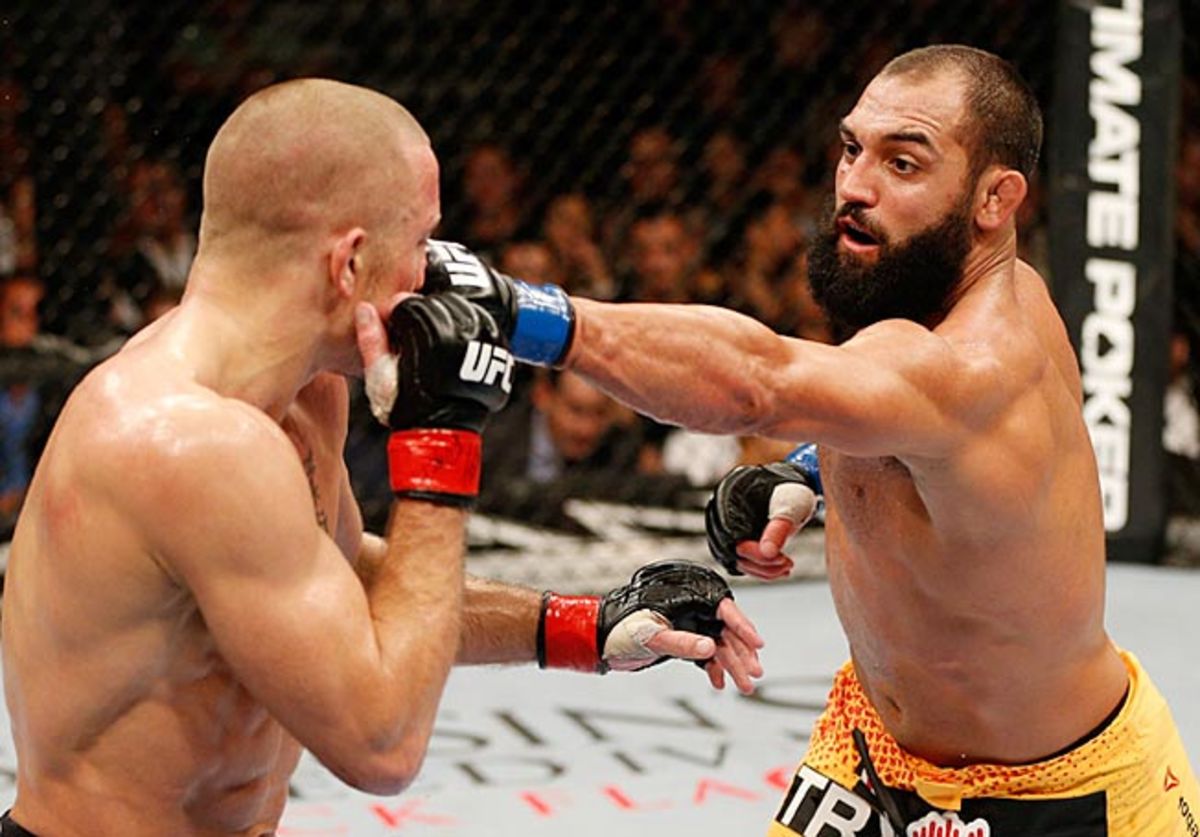 Georges St-Pierre (left) won a split-decision over Johny Hendricks, but took a beating in the process.