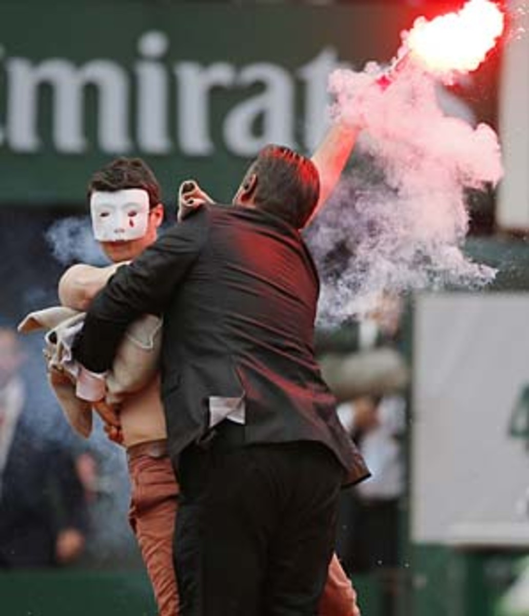A security guard grabs a demonstrator who ran on court. (Michel Spingler/AP)