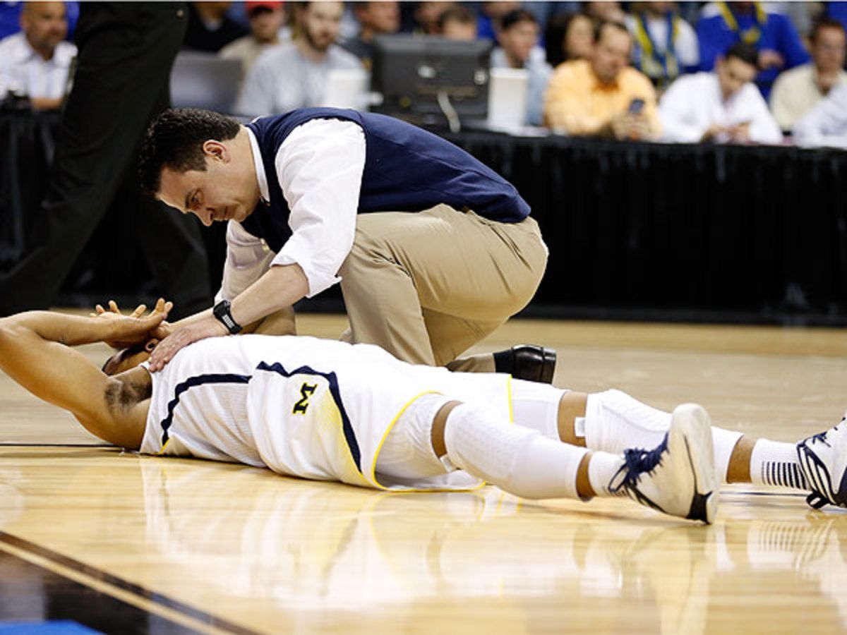 After getting tangled with Jackrabbits' Nate Wolters, Trey Burke hit the hardwood and was helped off by a trainer. (Gregory Shamus/Getty Images)