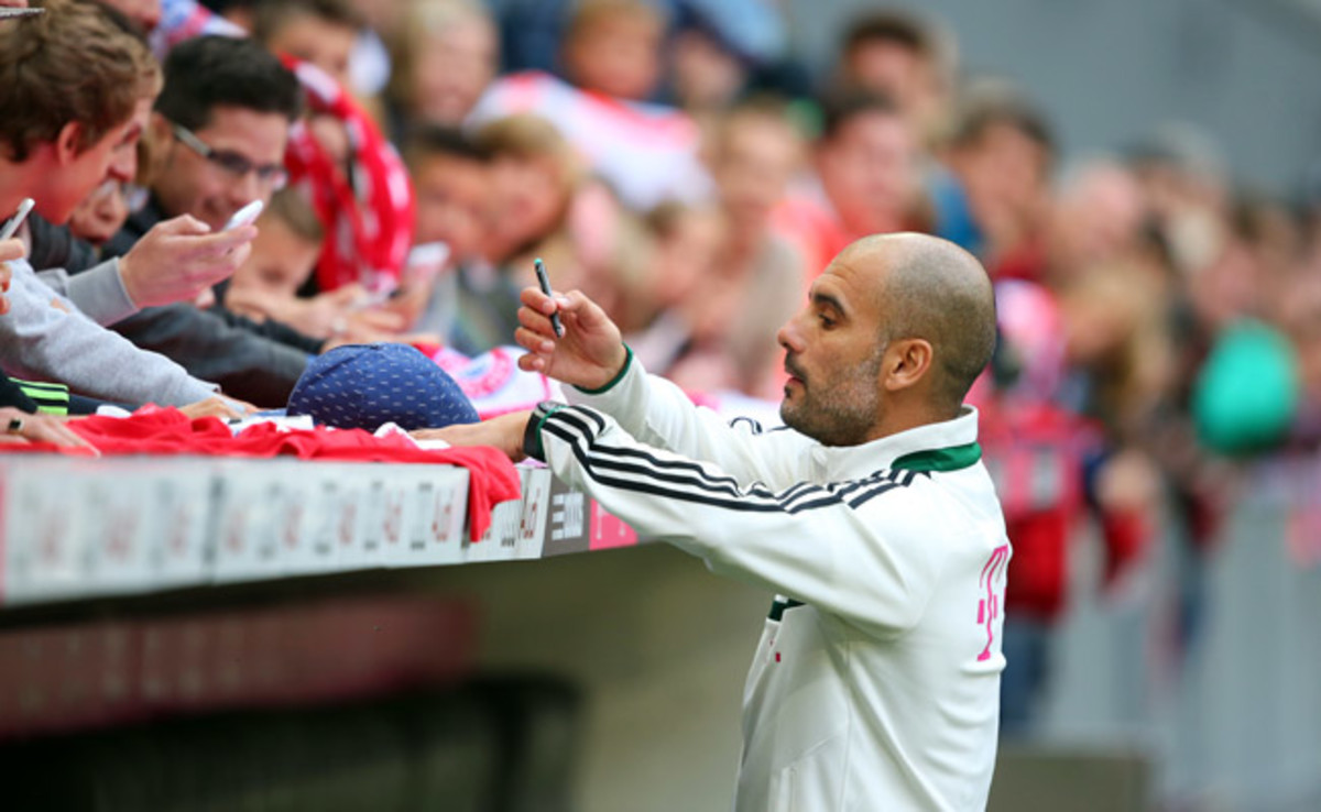 Pep Guardiola signs autographs for Bayern Munich fans who attended Guardiola's first training session.