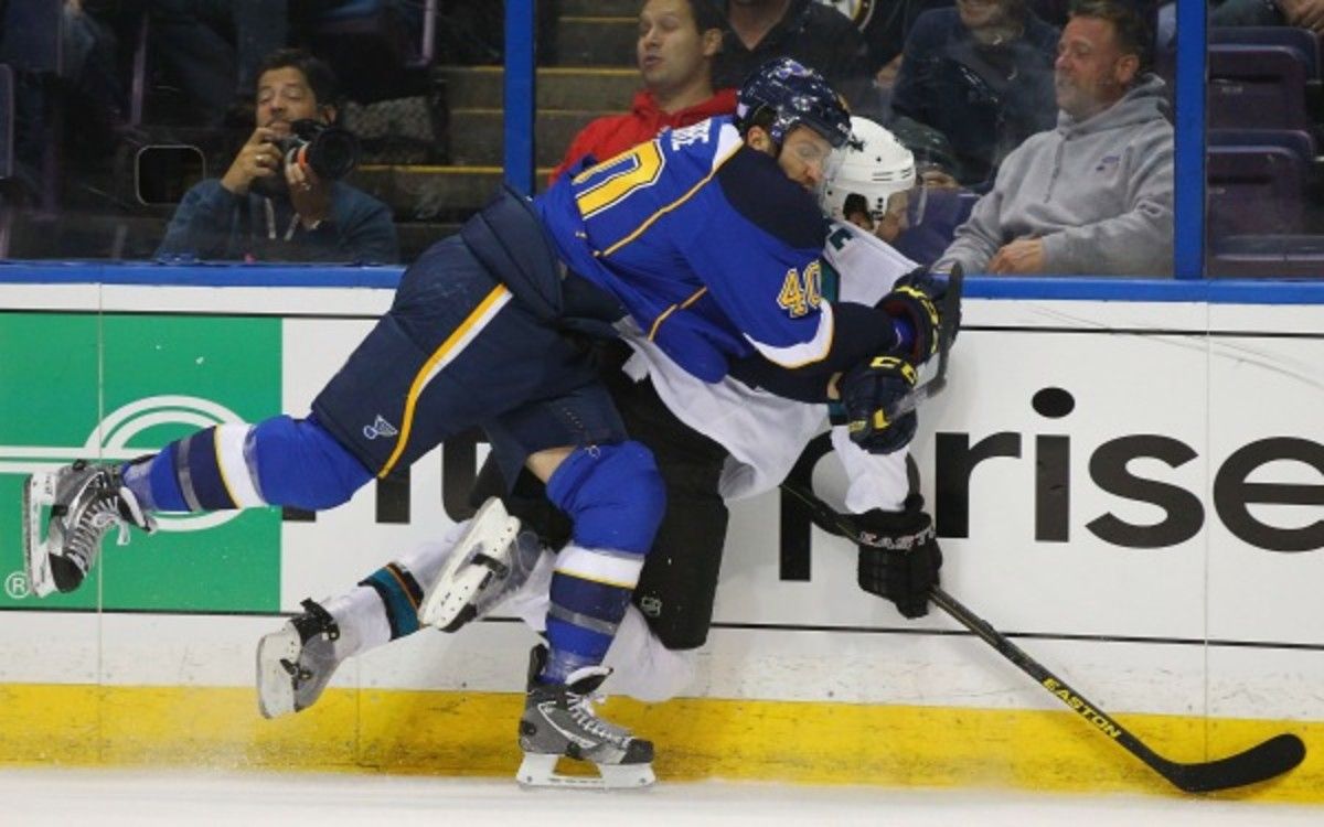 Dan Boyle is ran into the boards by Blues center Maxim Lapierre (Dilip Vishwanat/Getty Images)