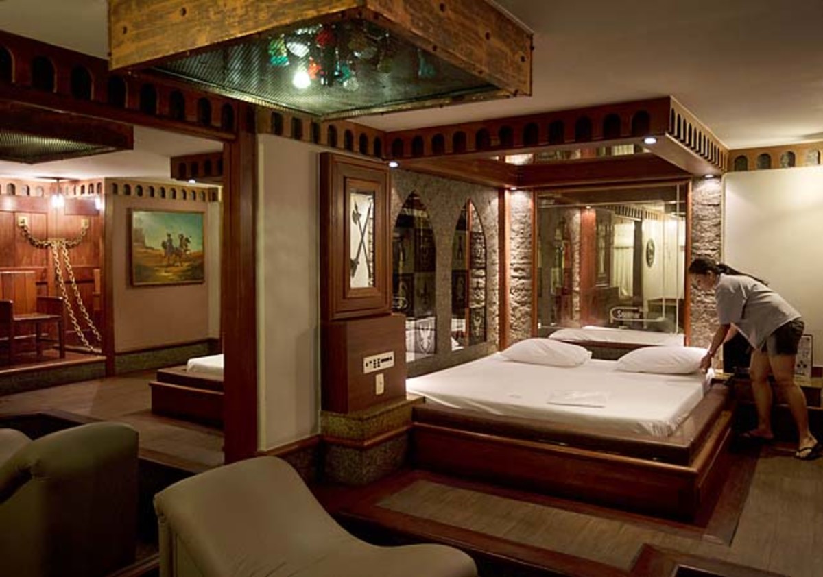 A worker makes the bed inside the Medieval Room, where chains hang on the wall, at the Shalimar Hotel.