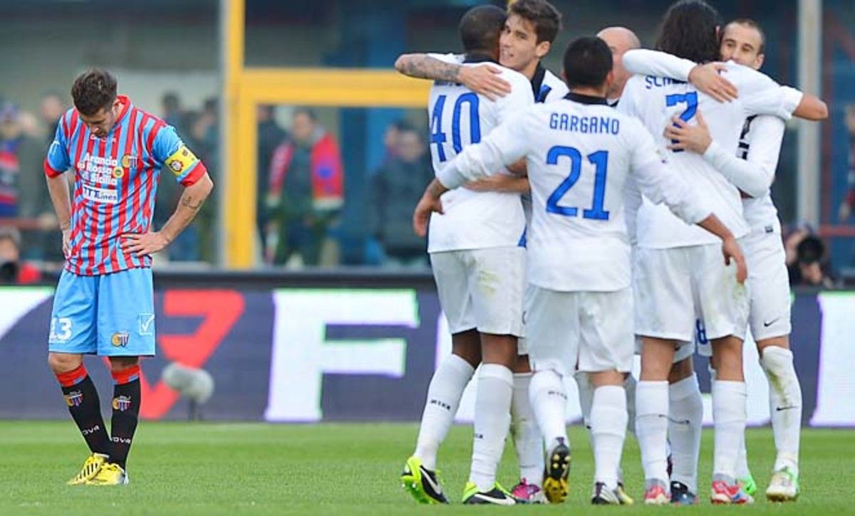Catania midfielder Mariano Izco (left) reacts as Inter Milan players celebrate their victory.