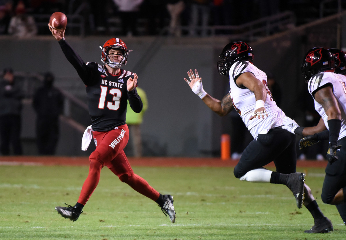 Devin Leary throws a pass on the run as Louisville defenders pursue 