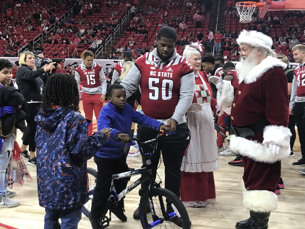 Center Grant Gibson assists Santa in presenting a youngster his new bicycle
