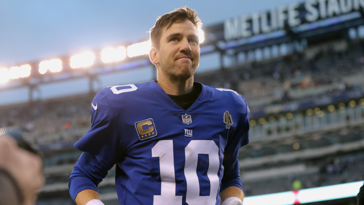 Giants QB Eli Manning runs off the field without his helmet on