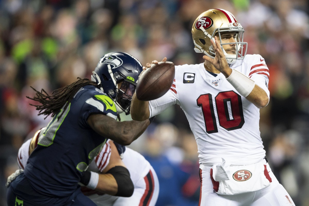 San Francisco 49ers quarterback Jimmy Garoppolo (10) passes the ball with Seattle Seahawks defensive end Jadeveon Clowney (90) chasing during the second half at CenturyLink Field. San Francisco defeated Seattle 26-21.