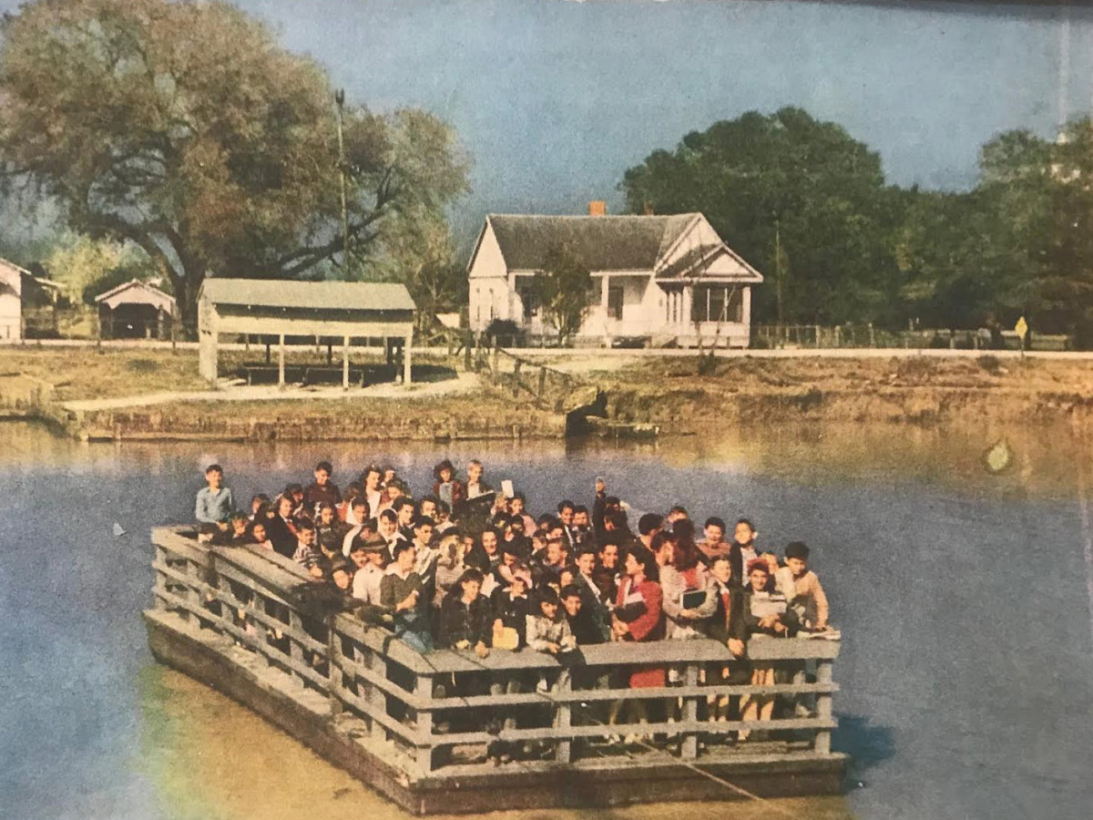 Children, their books in hand, crossed Bayou Lafourche for school on a ferry operated by Ed Orgeron's grandfather, Julian. He's pictured here during a ferry cross. He's the older man wearing the hat on the right front side of the ferry.