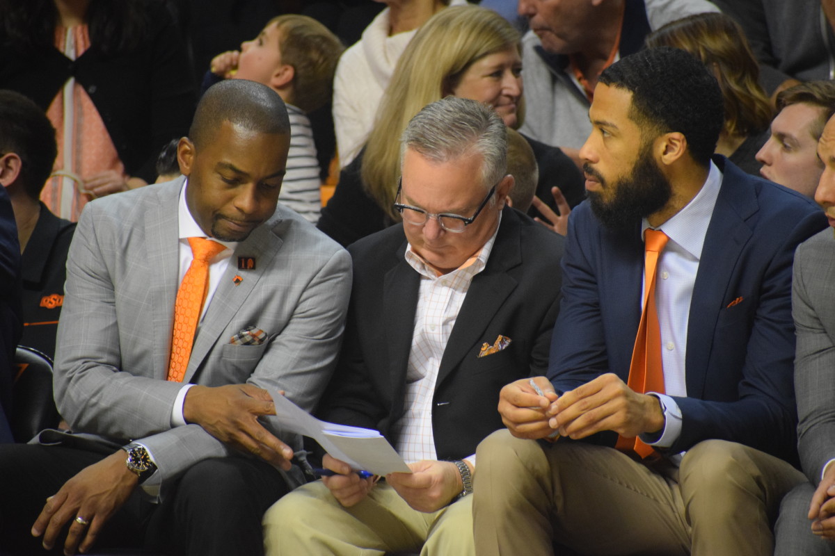 Barry Hinson takes notes on the bench during the game sitting between head coach Mike Boynton and assistant Cannen Cunningham. 