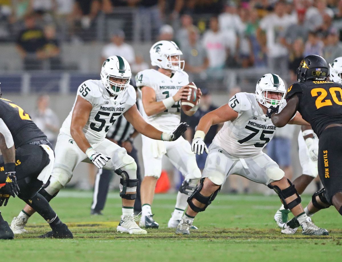 Michigan State Spartans offensive tackle Jordan Reid (55) and guard Kevin Jarvis (75) block for quarterback Brian Lewerke (14) against the Arizona State Sun Devils at Sun Devil Stadium.