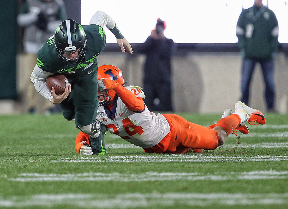 Michigan State Spartans quarterback Brian Lewerke (14) is dragged down by Illinois Fighting Illini linebacker Dawson DeGroot (24) during the second half of a game at Spartan Stadium. DeGroot (24) had a career-high 11 tackles in the Illini's 37-34 win over Michigan State on Nov. 9, 2019.