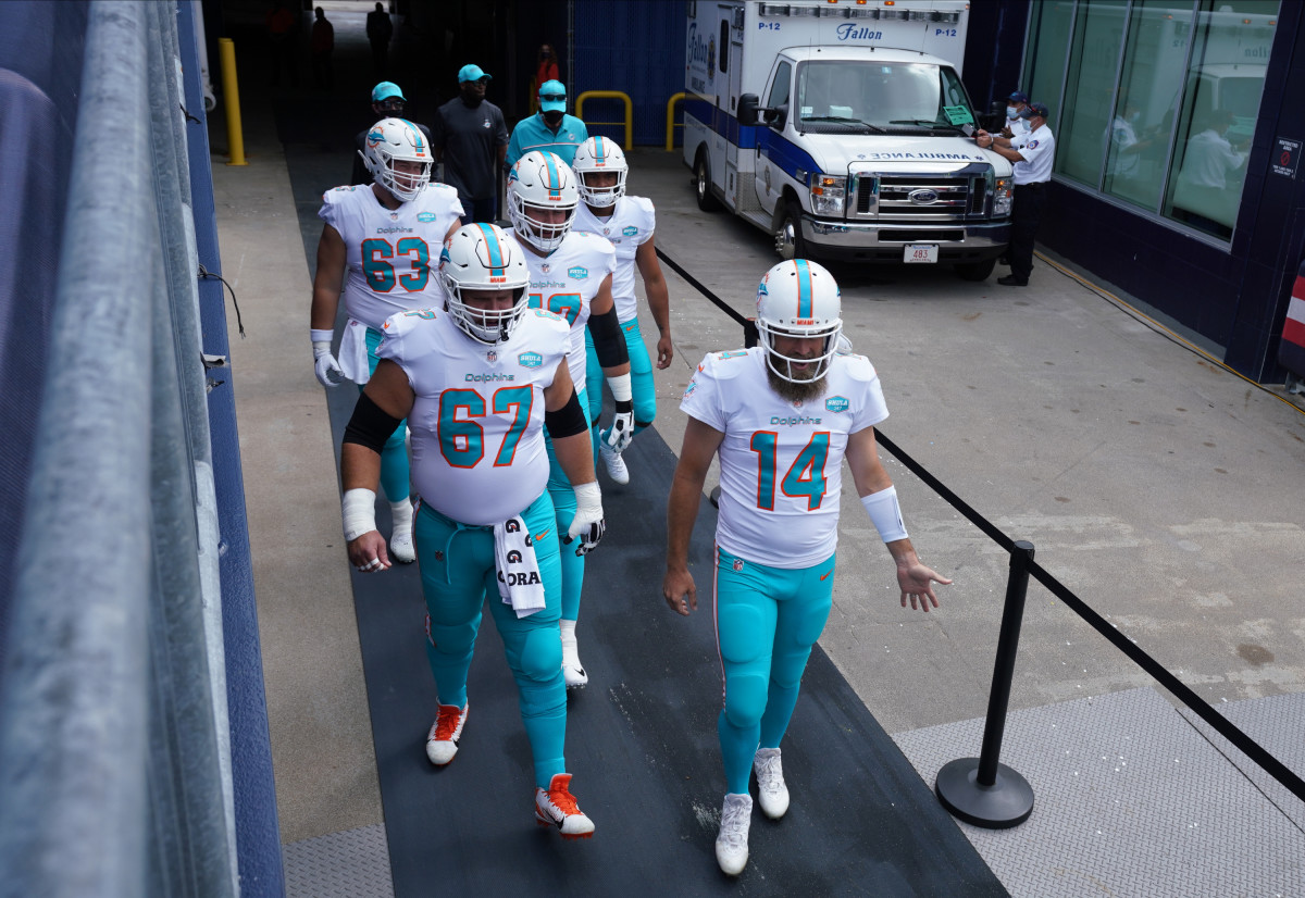 Miami Dolphins quarterback Ryan Fitzpatrick (14) and teammates, including center Ted Karras (67) take the field to warm up before the start of the game against the New England Patriots at Gillette Stadium.