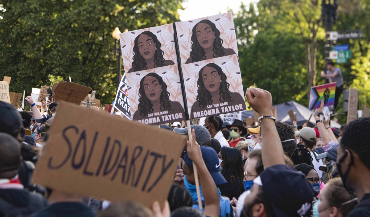 A protester holds a sign bearing portraits of Breonna Taylor, who was shot by police in her home on March 13 during protests against the killing of black people by police in Washington, DC