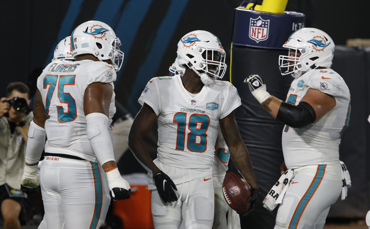 Miami Dolphins wide receiver Preston Williams (18) celebrates with center Ted Karras (right) and offensive guard Ereck Flowers (75) after making a touchdown catch against the Jacksonville Jaguars during the first quarter Thursday night at TIAA Bank Field.