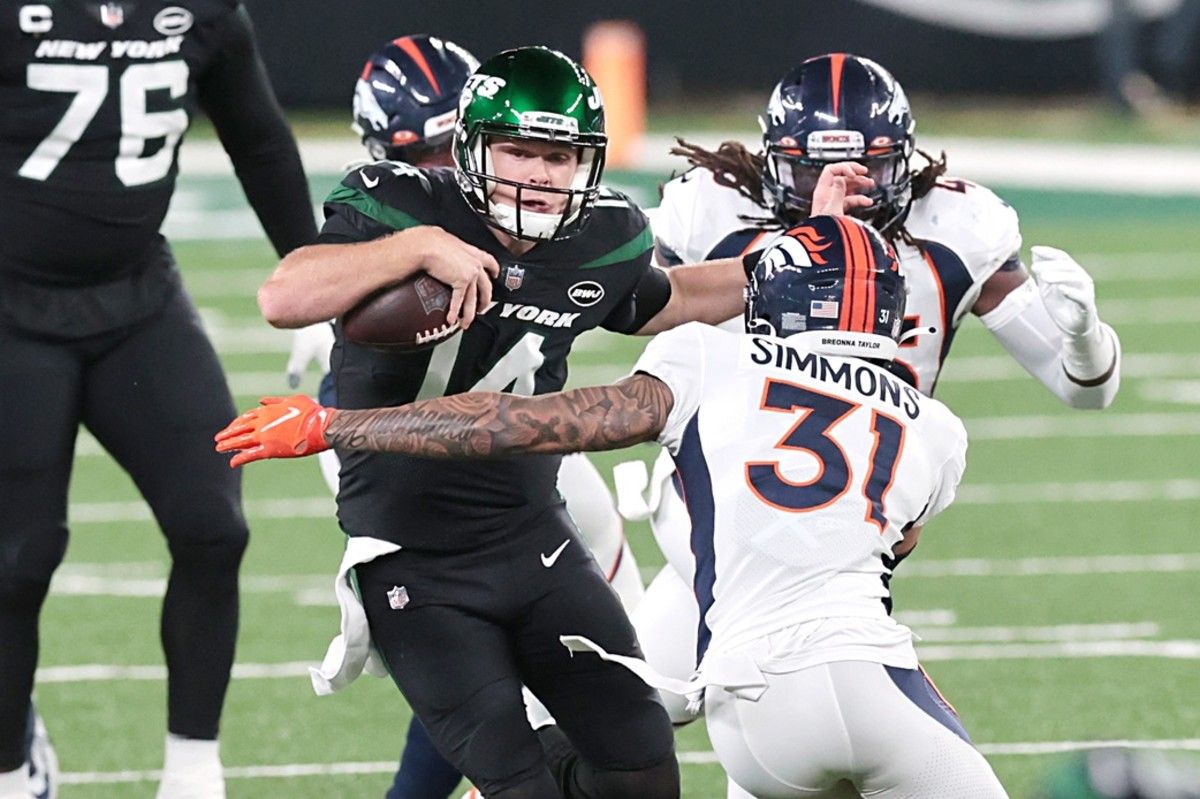 New York Jets quarterback Sam Darnold (14) breaks a tackle by Denver Broncos free safety Justin Simmons (31) for a touchdown at MetLife Stadium.